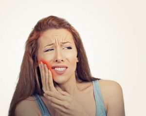 woman holding jaw in pain